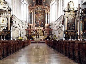 Mittelschiff der dreischiffigen Hallenkirche in Dillingen mit prunkvoll verzierten Säulen, dem Altar und Sitzbänken.