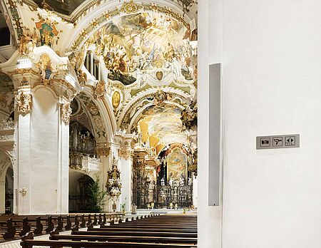 An einer Säule in der Klosterkirche Einsiedeln, hängt eine Fohhn Linea LX-150 mit Blick in das Hauptschiff.